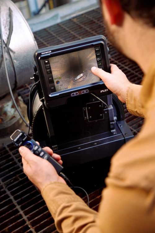 Operatore specializzato nelle ispezioni di saldature mentre utilizza un videoscopio Olympus IPLEX con endoscopio da 30 m per ispezionare tubazioni di processo mediante il joystick leggero per controllare la sonda di inserimento.